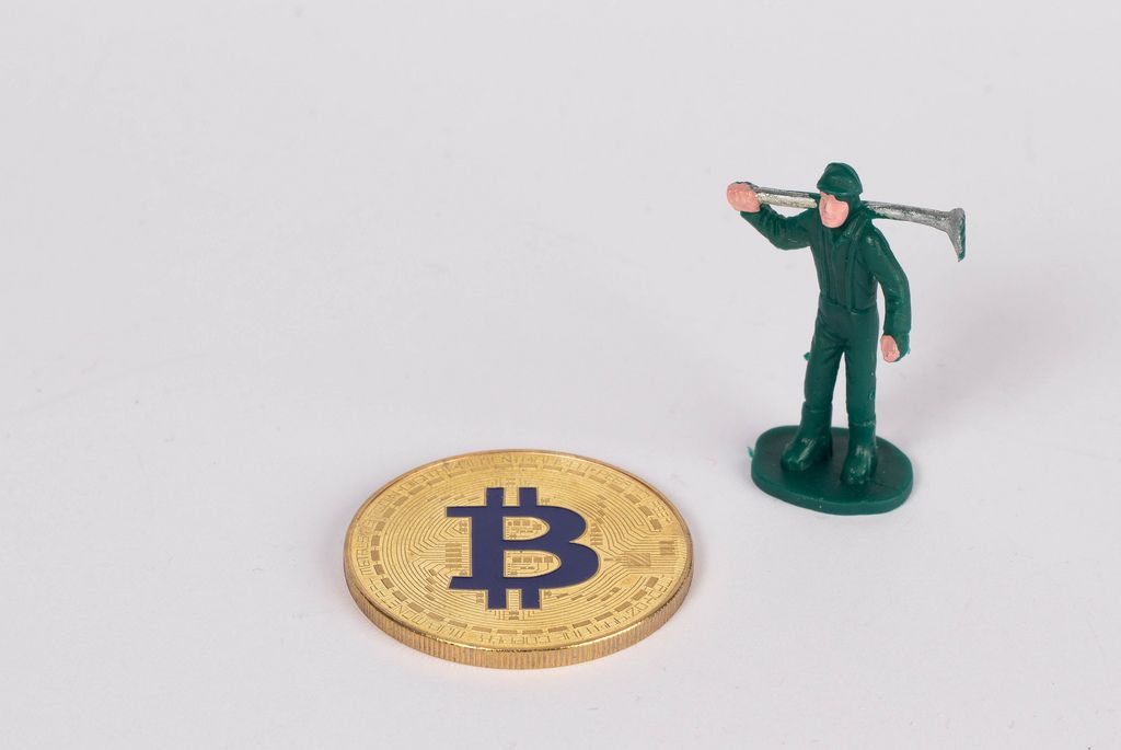Goldener Bitcoin und Minenarbeiter vor weißem Hintergrund