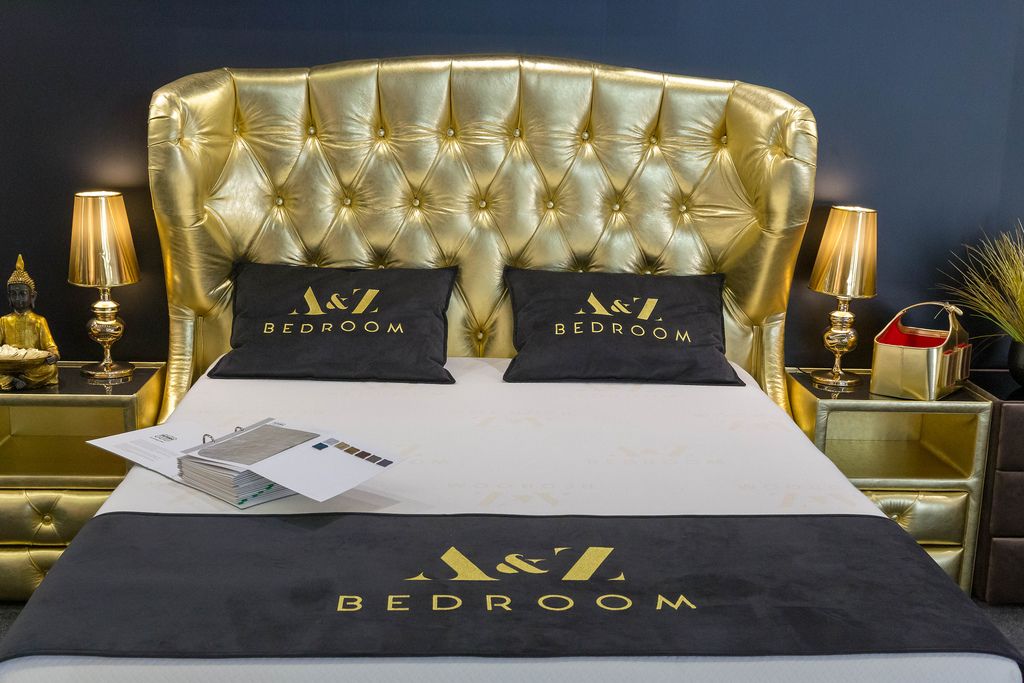 Goldenes Bett neben goldenen Lampen und Tischen und einer Buddhafigur in luxuriösem Hotelzimmer