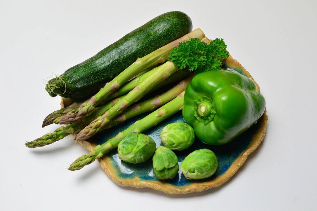 Grünes Gemüse - Grüne Paprika mit Rosenkohl, grünem Spargel, Zucchini un Petersilie auf blauem Tonteller