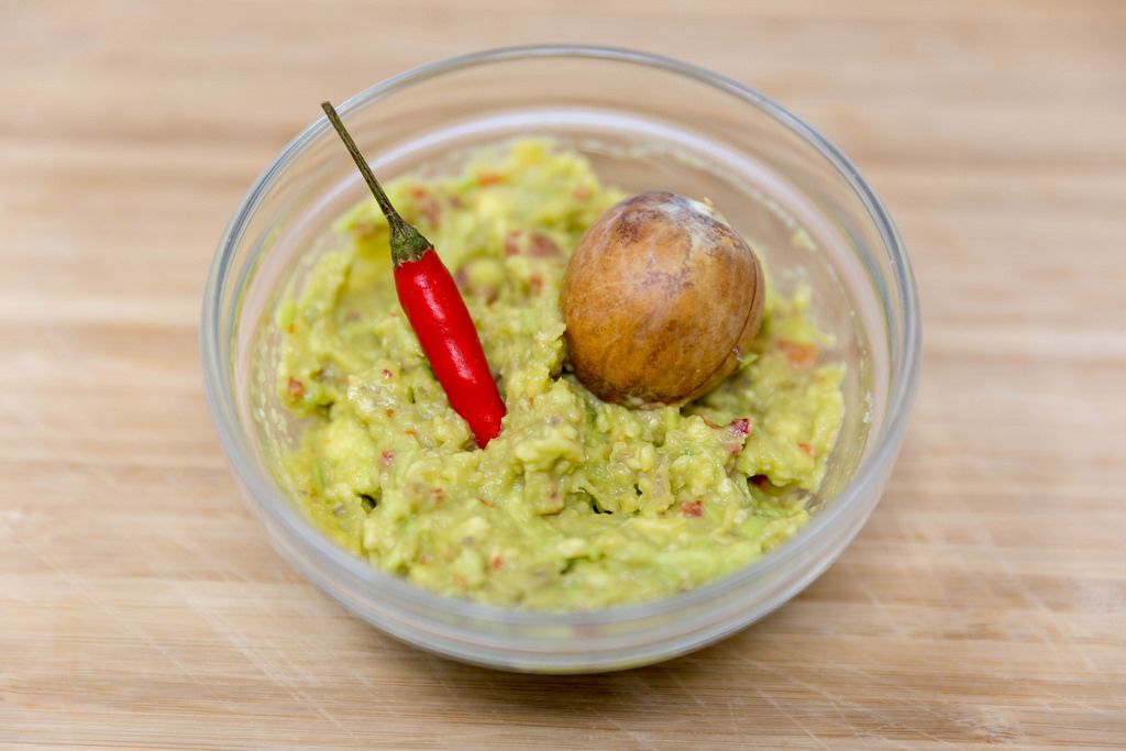 Guacamole Avocado Dip - with red chili pepper and avocado kernel in glas bowl