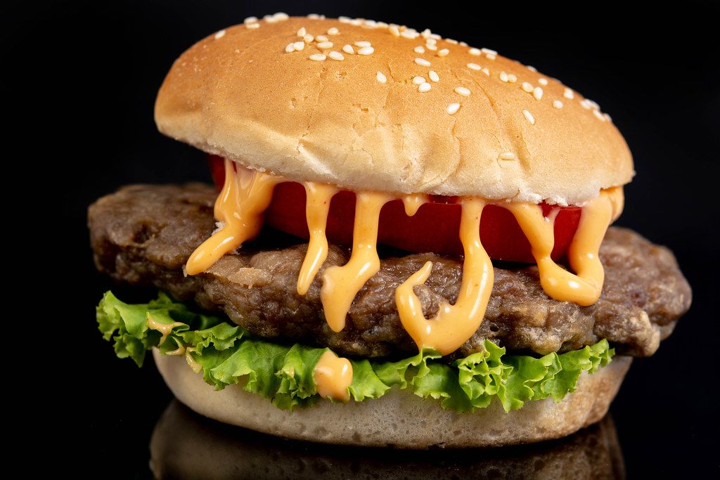 Hamburger with Tomato Lettuce and Sauce above black background