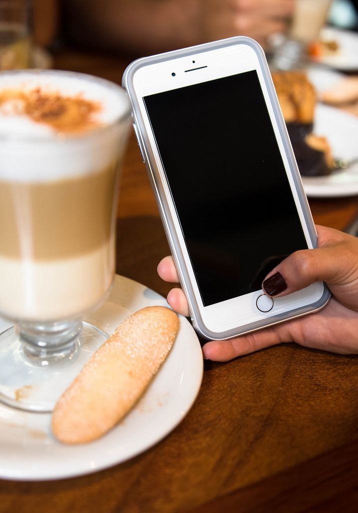 Hand holding a phone in a coffee shop