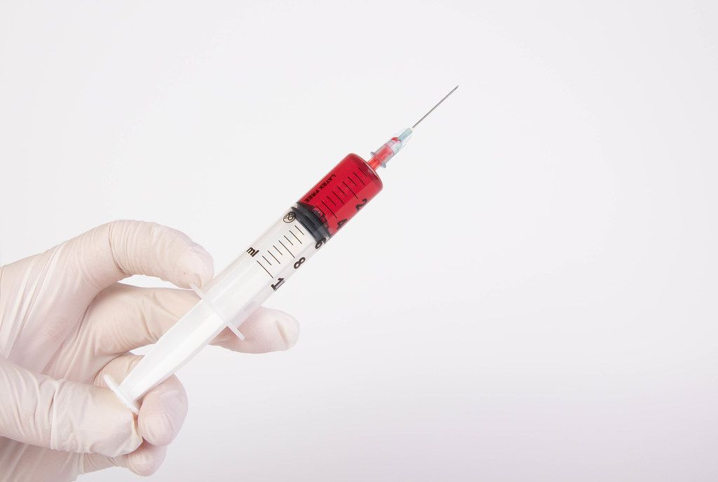 Hand holding blood syringe for injection isolated on white background