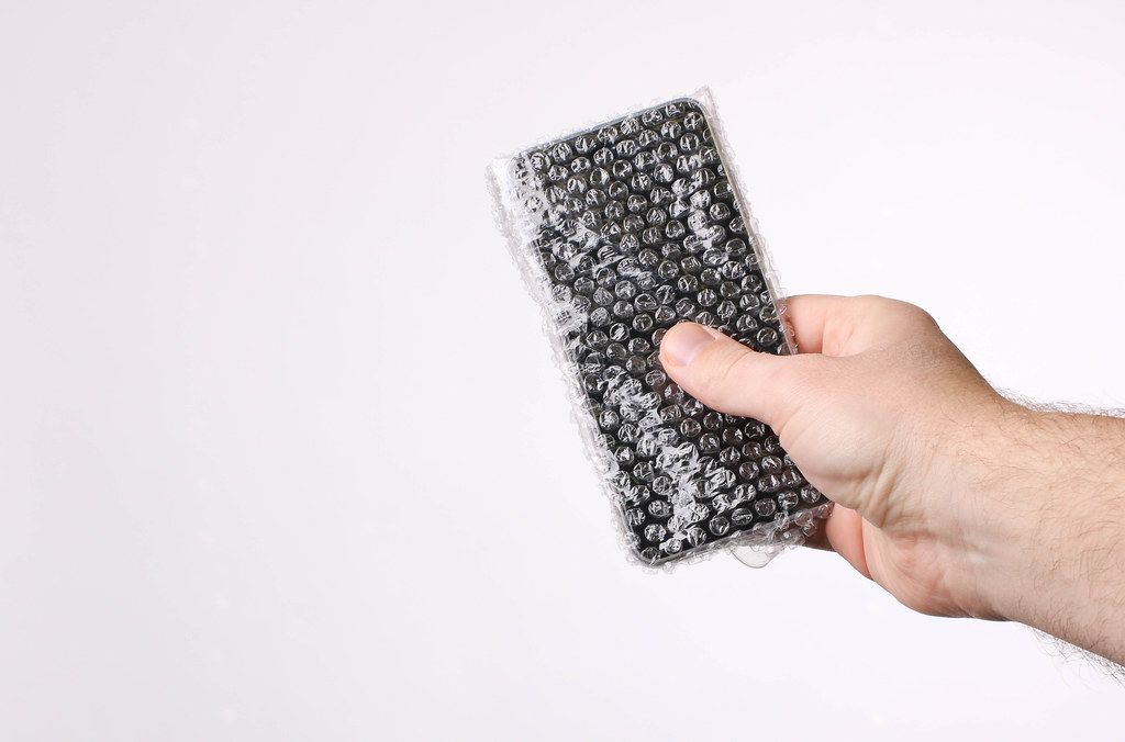 Hand holding mobile phone packed in bubble wrap