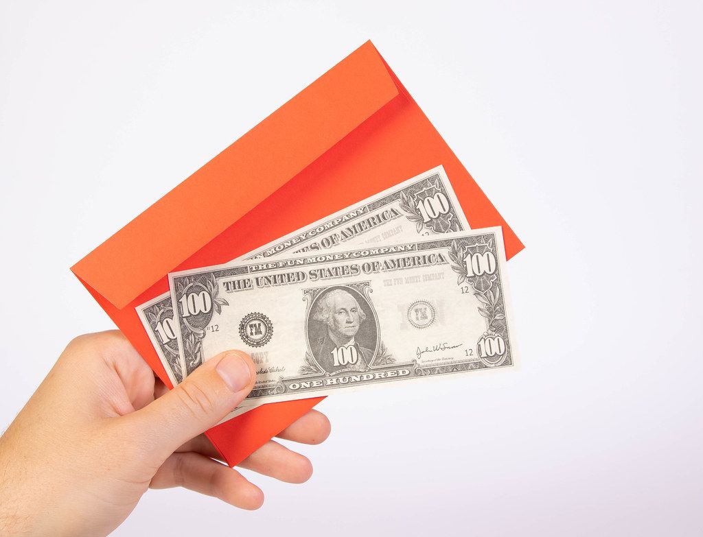 Hand holding red envelope and money