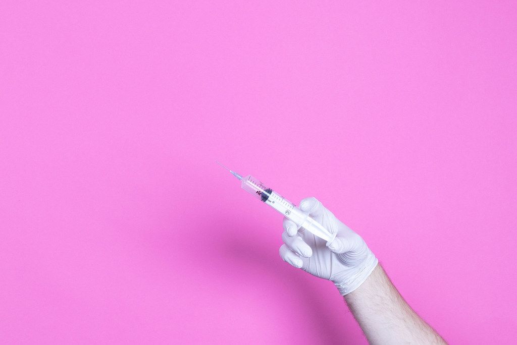 Hand in medical glove holding syringe