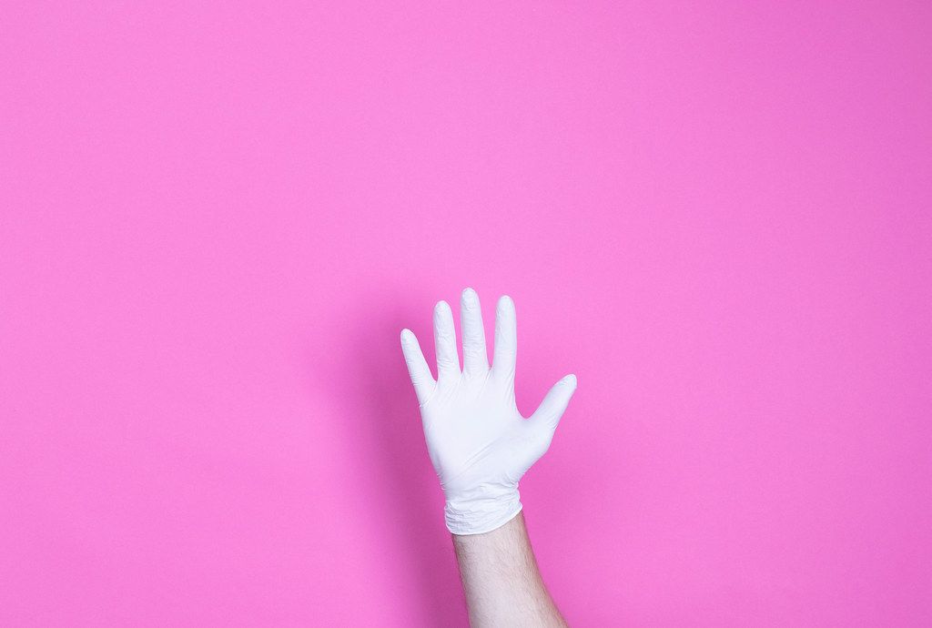 Hand in medical glove on pink background