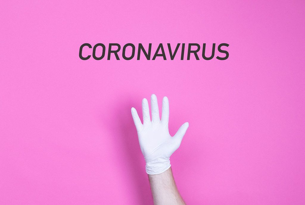 Hand in medical glove with Coronavirus text