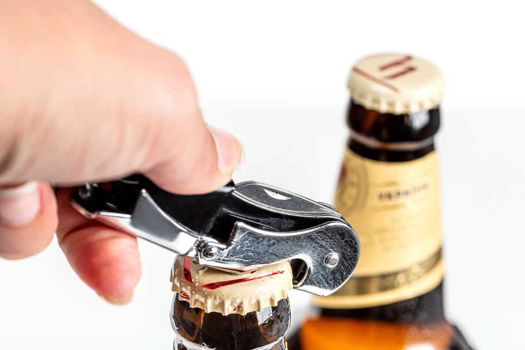 Hand opens a bottle of beer, close up