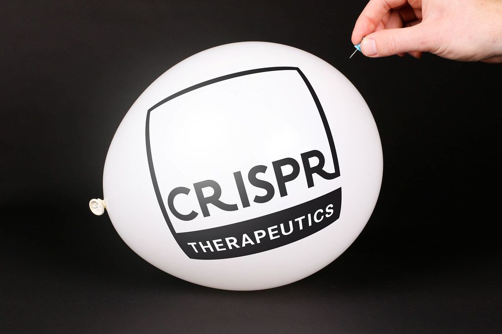 Hand uses a needle to burst a balloon with CRISPR Therapeutics logo