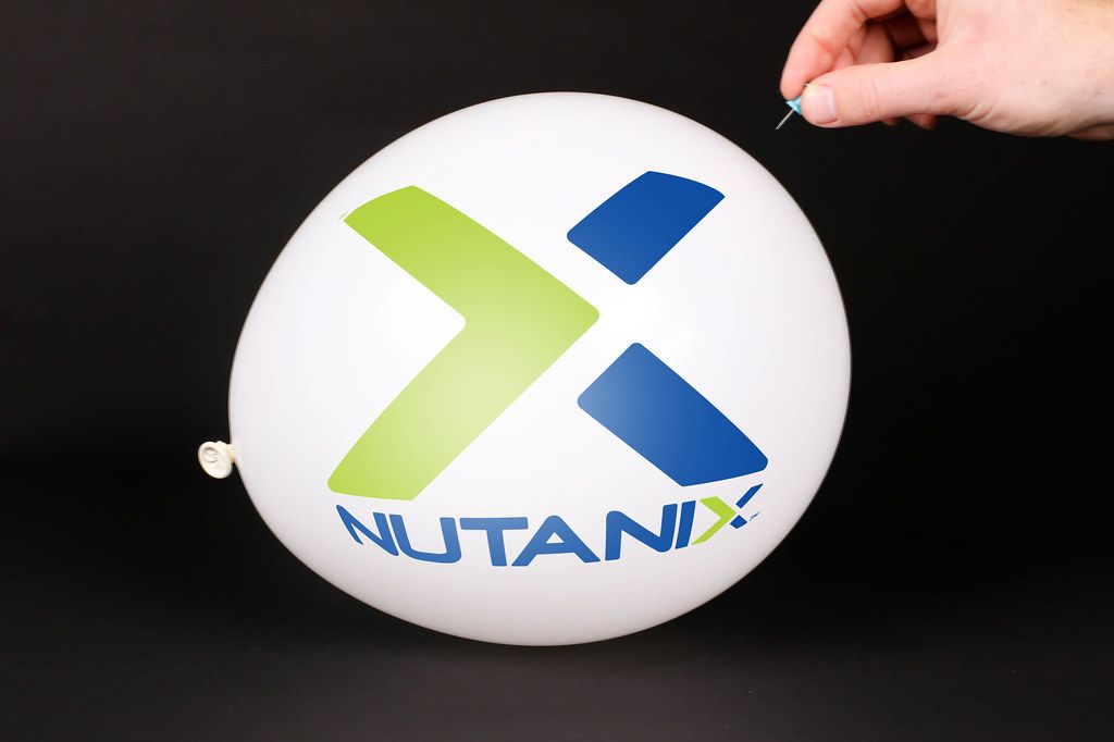 Hand uses a needle to burst a balloon with Nutanix logo