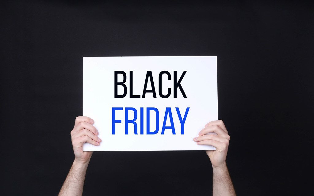 Hands holding board with Black Friday text against black background