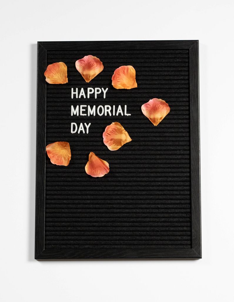 Happy memorial day auf einem schwarzen Brett mit Blumenblättern