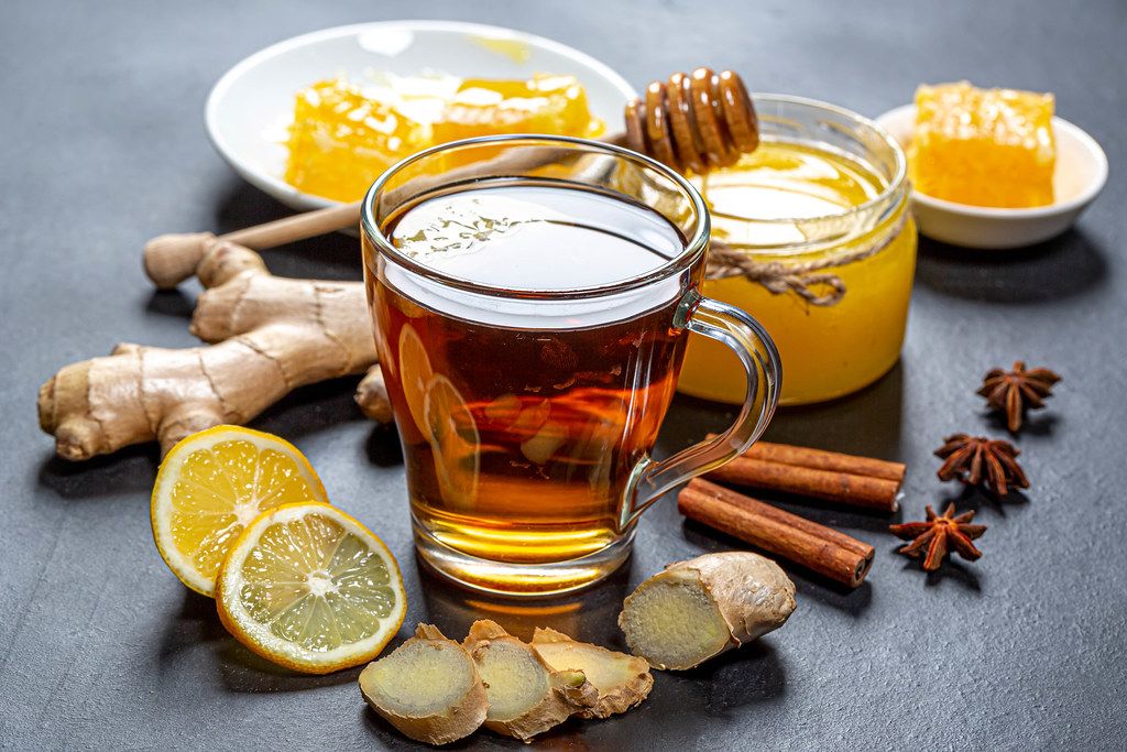 Healthy tea with ginger, honey, lemon and spices on black background