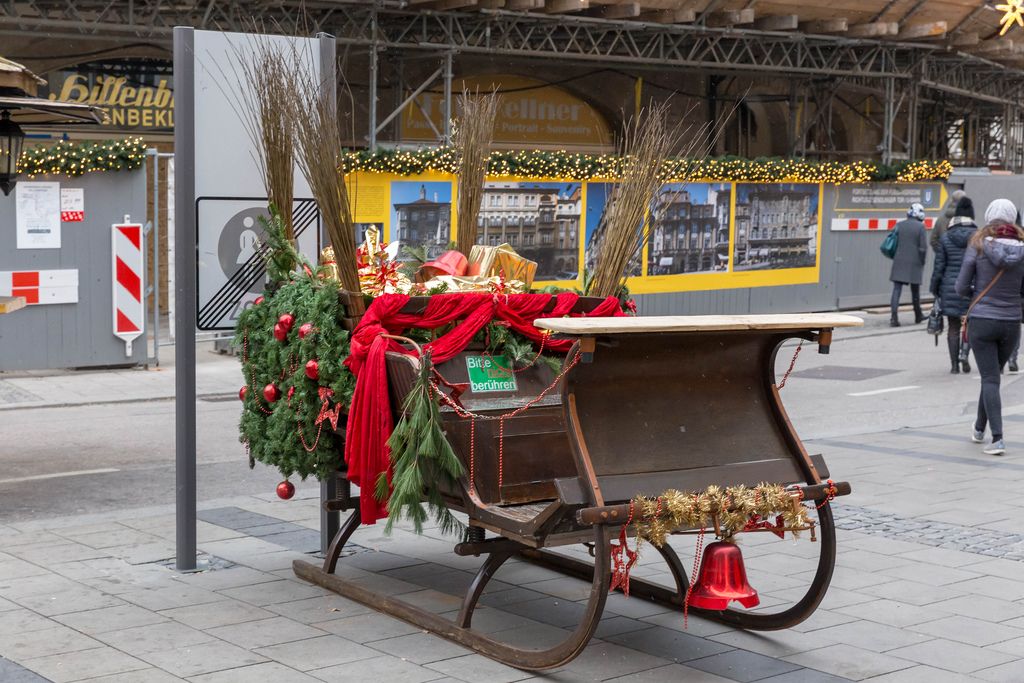 Hölzerner Weihnachtsschlitten, dekoriert mit Tannenzweigen, Geschenken und Nikolausruten