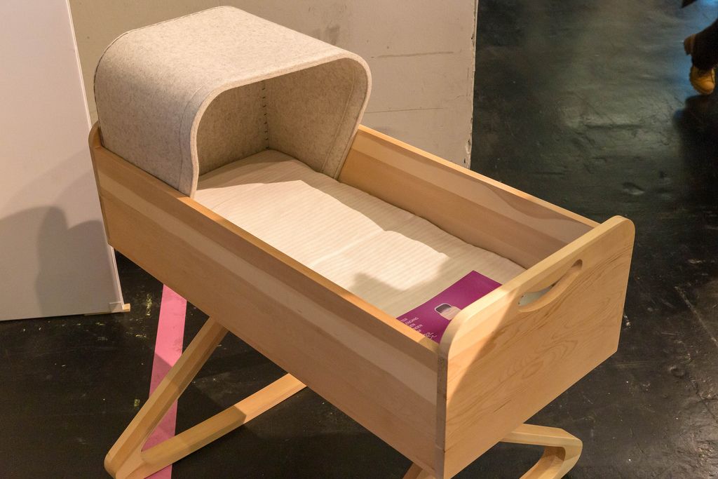 Hölzernes Babybett in Form einer Schublade mit Füßen in Form von Kleiderbügeln