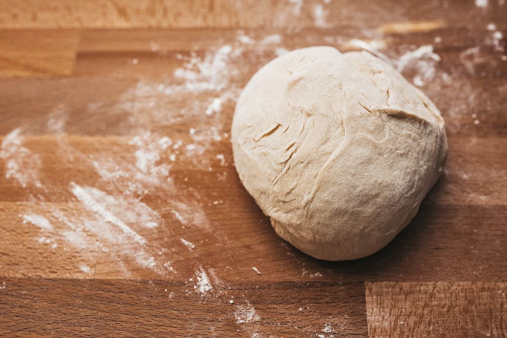 Homemade dough on floured wooden board