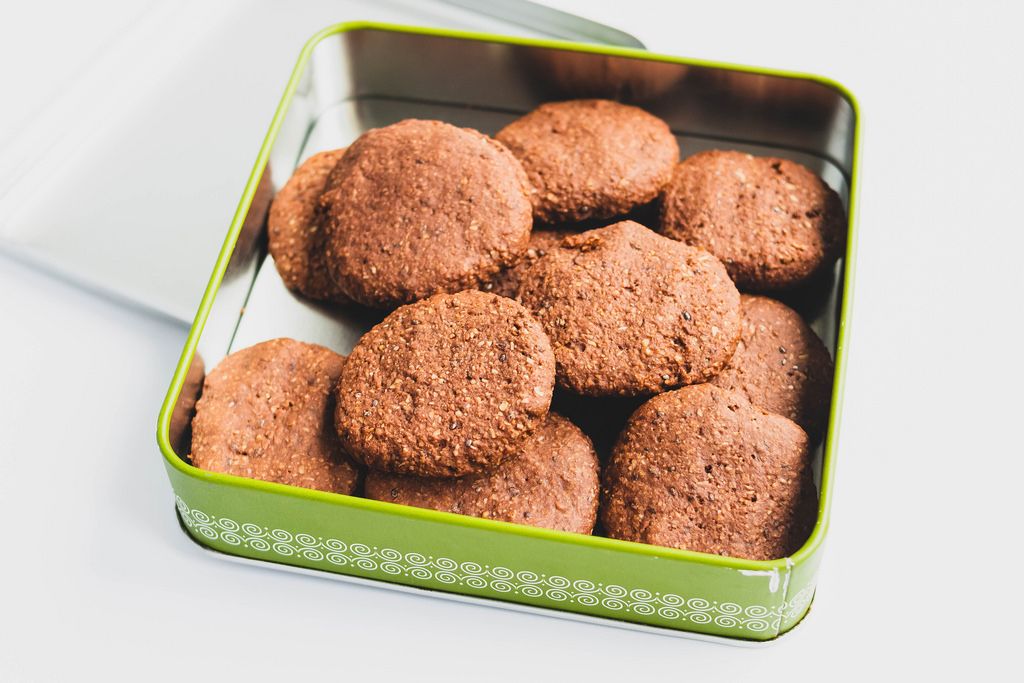 Homemade vegan cocoa cookies in a tin box on white background