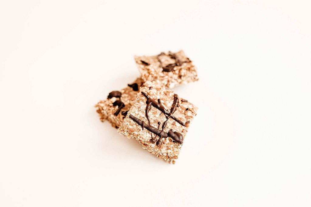 Homemade vegan granola bar with melted chocolate on white background