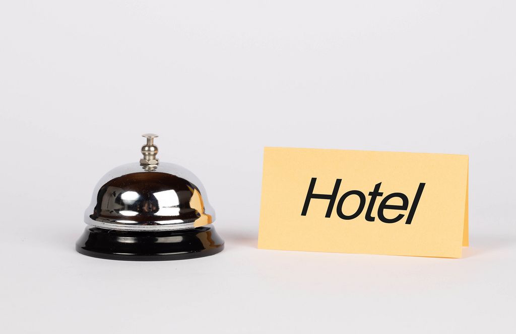 Hotelklingel und gelbes Papier mit dem Wort HOTEL auf weißem Hintergrund