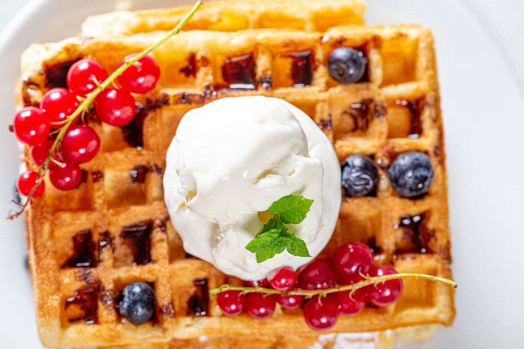 Ice cream with mint leaves and fresh berries on Belgian waffles