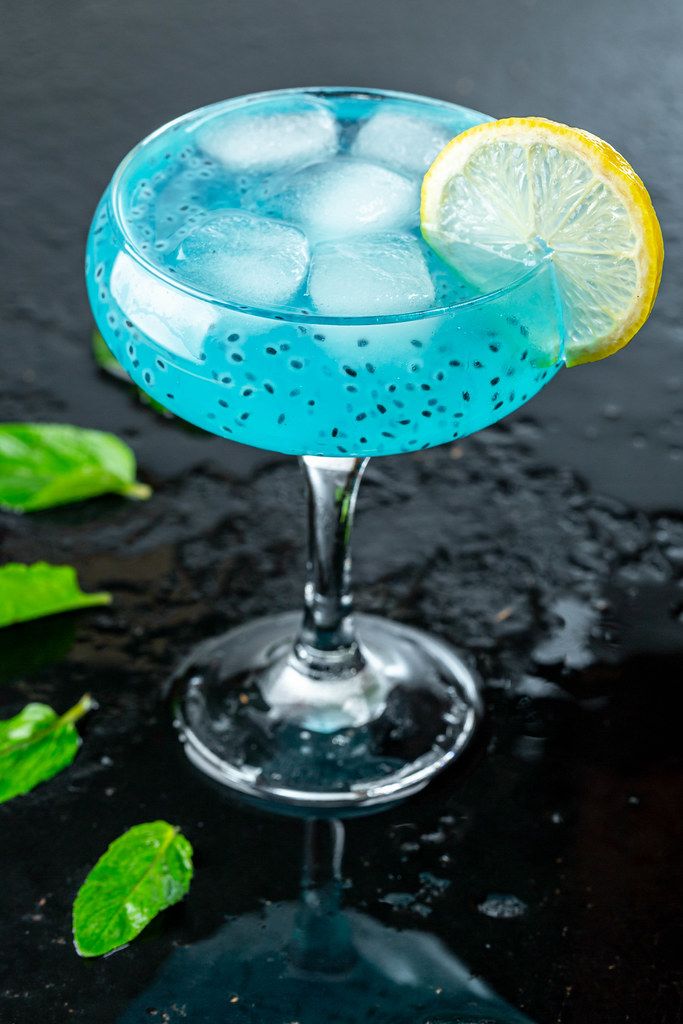 Kalter bläulicher Cocktail im Cocktailglas, mit Eiswürfeln, einem ...