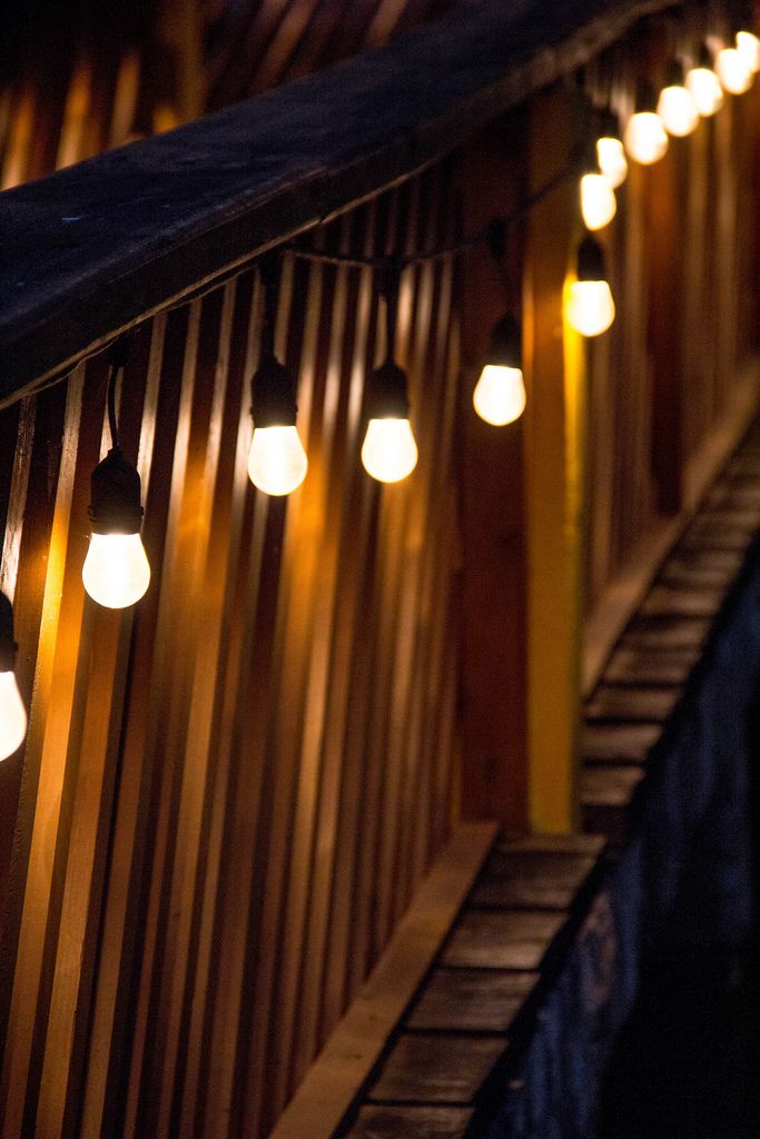 Kette von beleuchteten Glühbirnen dekoriert eine Holzbrücke