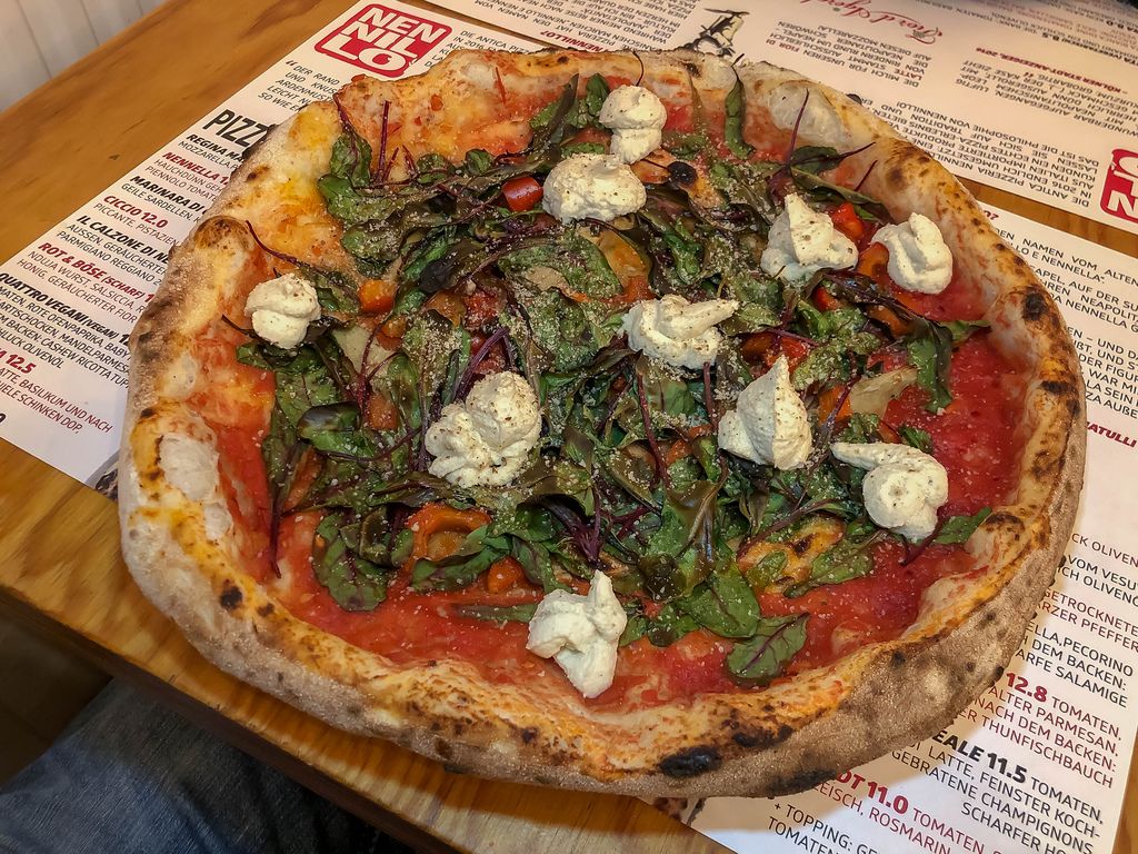 Knusprige Pizza in Pizzeria mit frischem Basilikum und nicht geschmolzenem Mozzarella Käse
