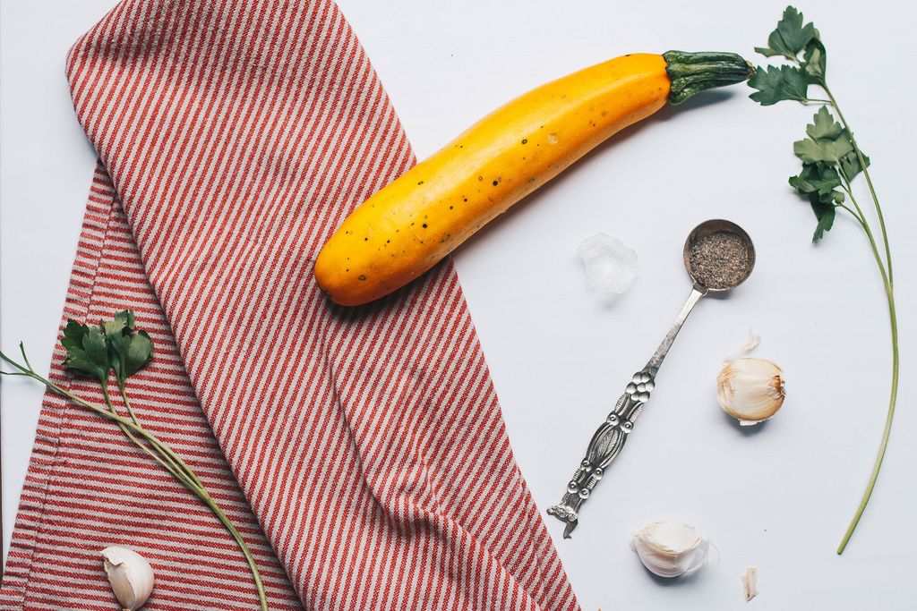 Küchen-Motiv: gelbe Zucchini, Knoblauch und Kräuter