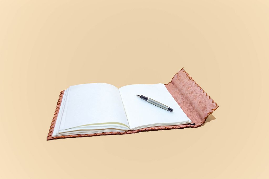 Leather notepad with blank pages and pen on cream background
