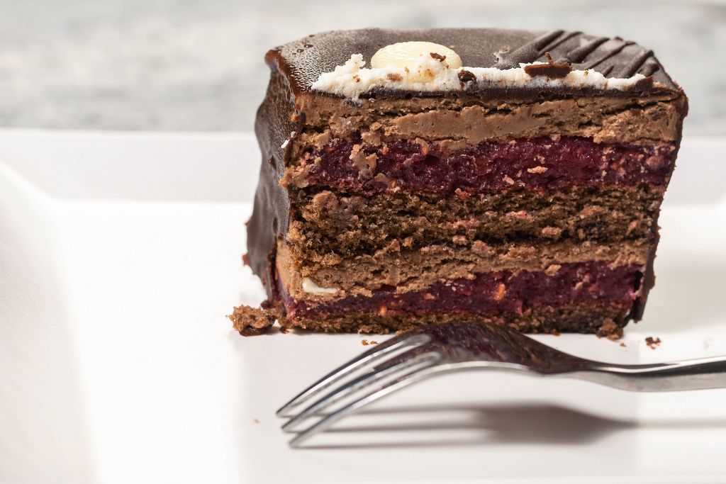 Leckeres Stück Schokoladenkuchen mit Kirschen und Schokoladenglasur auf Dessertteller