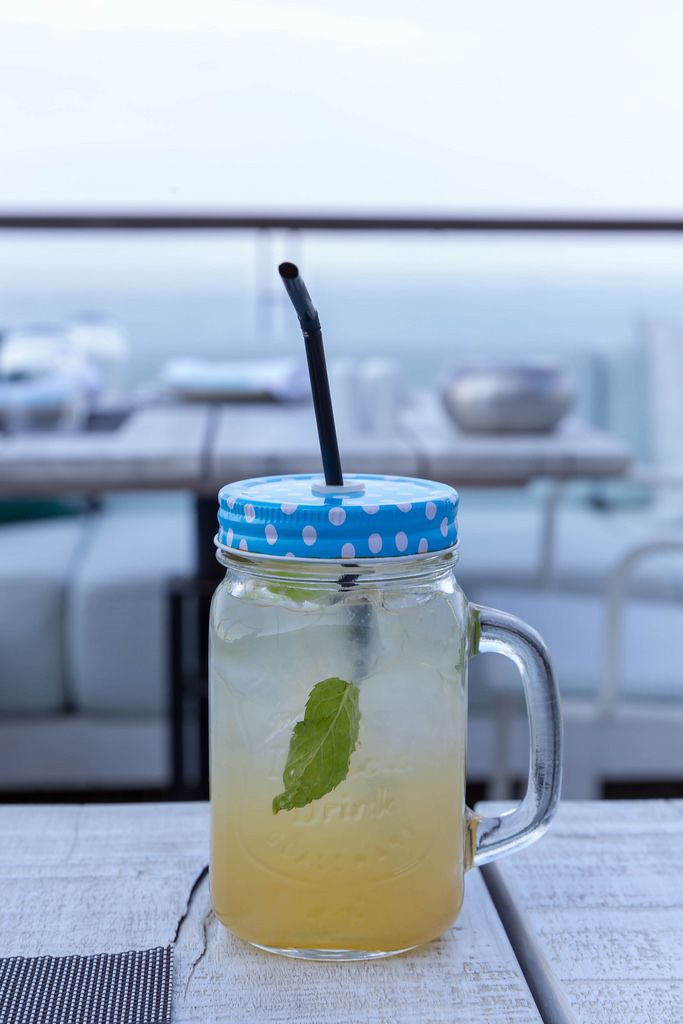 Lemonade with mint and ice in a half-liter glass with lid and drinking straw