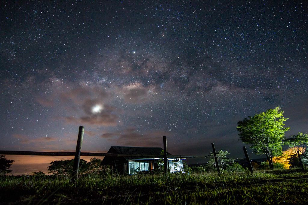 Leuchtender Sternenhimmel über in Feldern stehendem Haus in Don Salvador, Philippinen