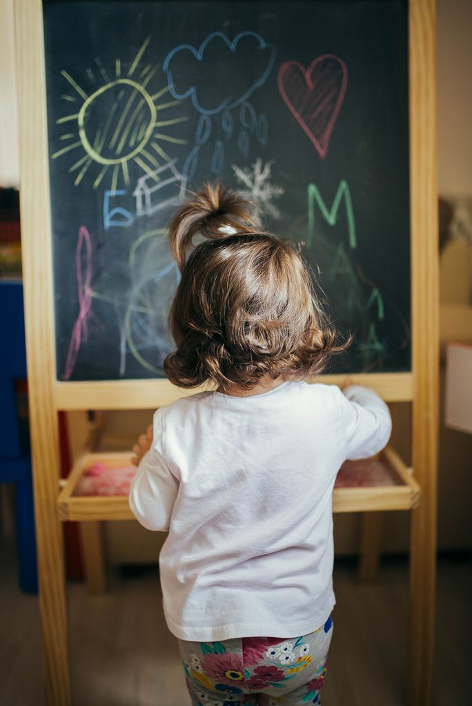 Little girl learning to draw and write on the black board