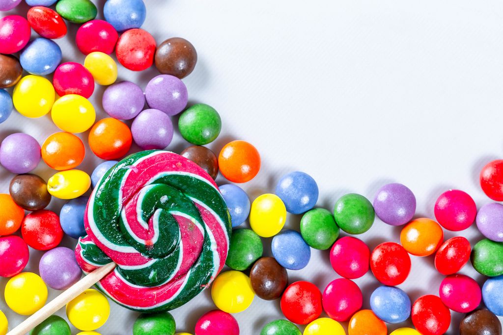 Lollipop liegt auf bunten Süßigkeiten in Kugelform auf weißem Hintergrund