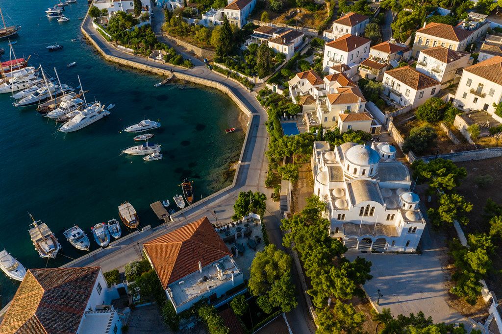 Luftbild einer griechischen Kirche und des malerischen Hafens vor der griechischen Insel Spetses in der Ägäis