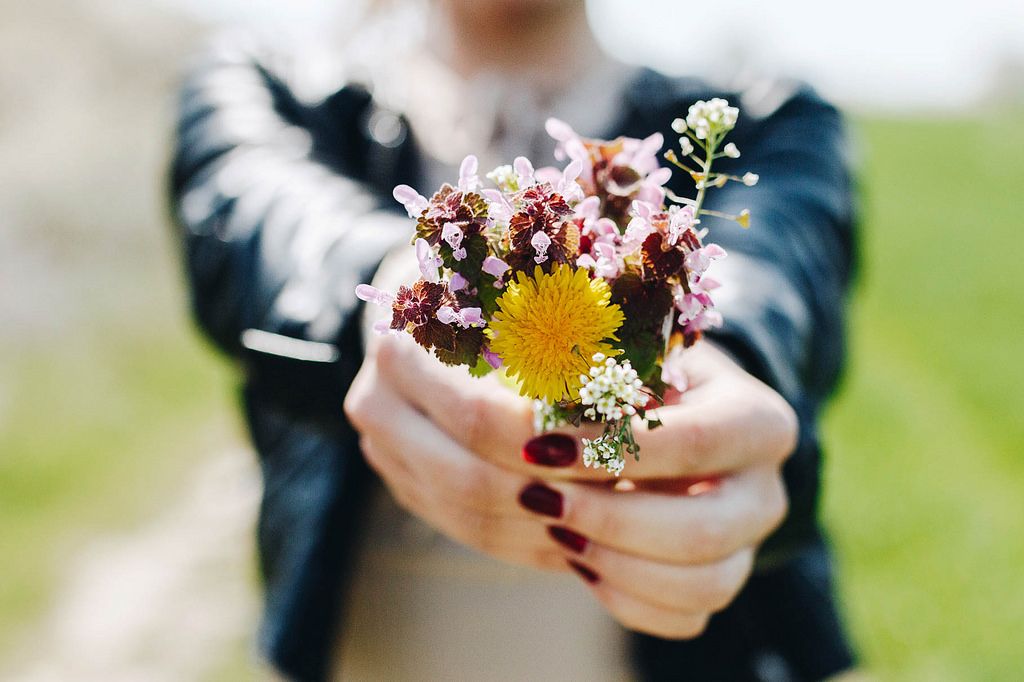 Mädchen hält einen Blumenstrauß mit Wildblumen in Händen. Scharfe Blumen und verschwommener Hintergrund