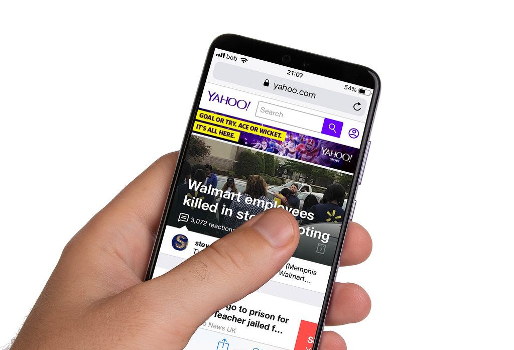 Male hands holding smartphone with an open Yahoo! website