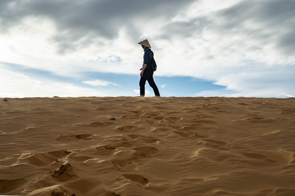Man standing on Top of a Sand Dune in the Red Sand Dunes of Mui Ne, Vietnam