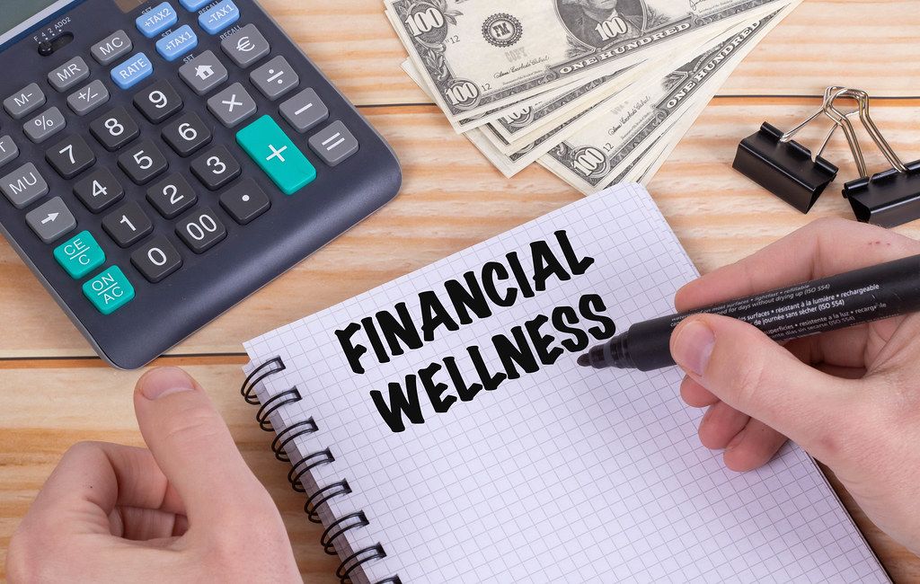 Man writing Financial wellness text in notebook