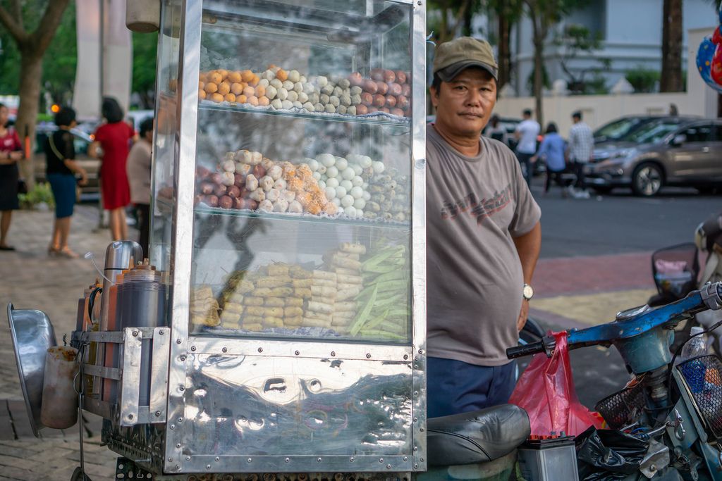 Mann bietet frittierte Snacks aus Verkaufsstand auf Motorroller an, Flower Street, Ho Chi Minh City, Vietnam
