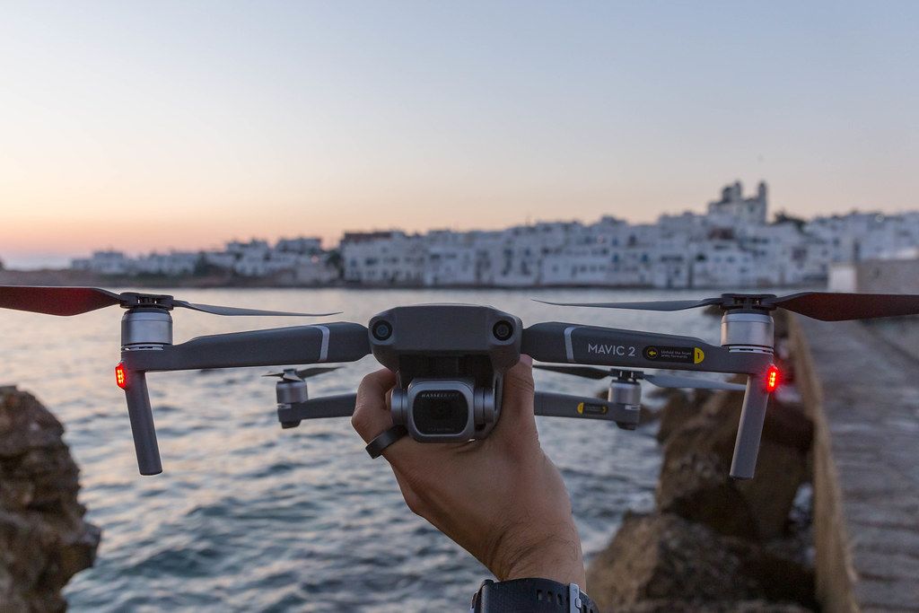 Mann hält die Drohne DJI Mavic 2 in der Hand, um sie über das Mittelmeer und die Insel Paros, Griechenland, fliegen zu lassen
