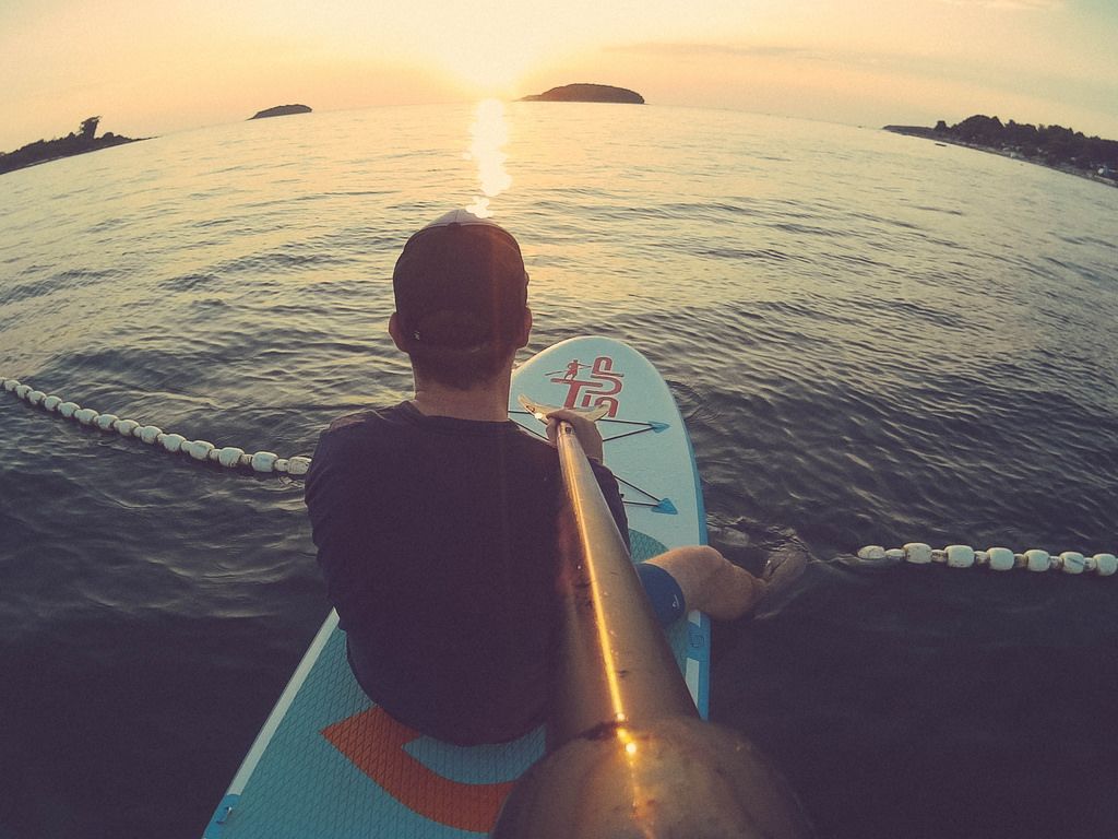 Mann schaut sich den Sonnenuntergang auf einem Paddelbrett an