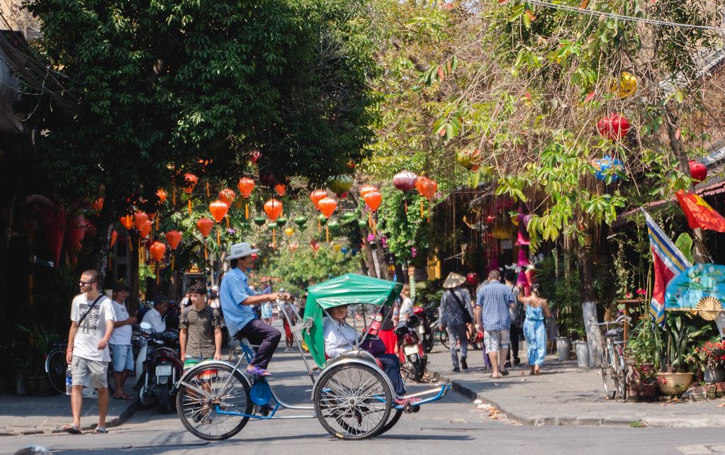 Männer auf einem Fahrrad auf einer geschmückten Straße der Küstenstadt Hoi Ann, Vietnam