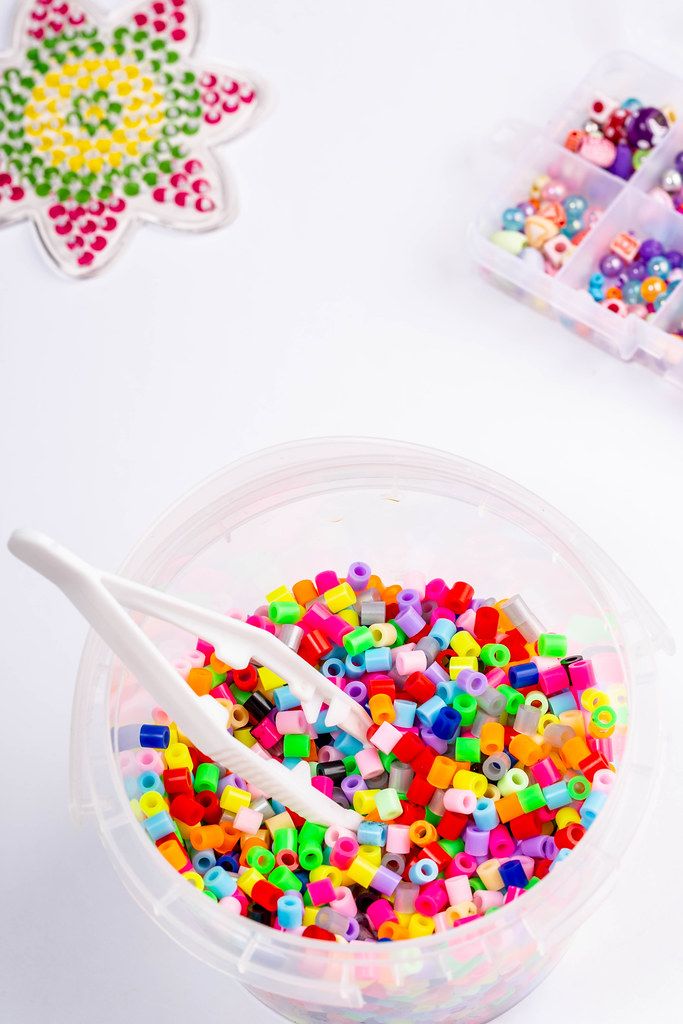 Many little beads with tweezers on white background (Flip 2019)