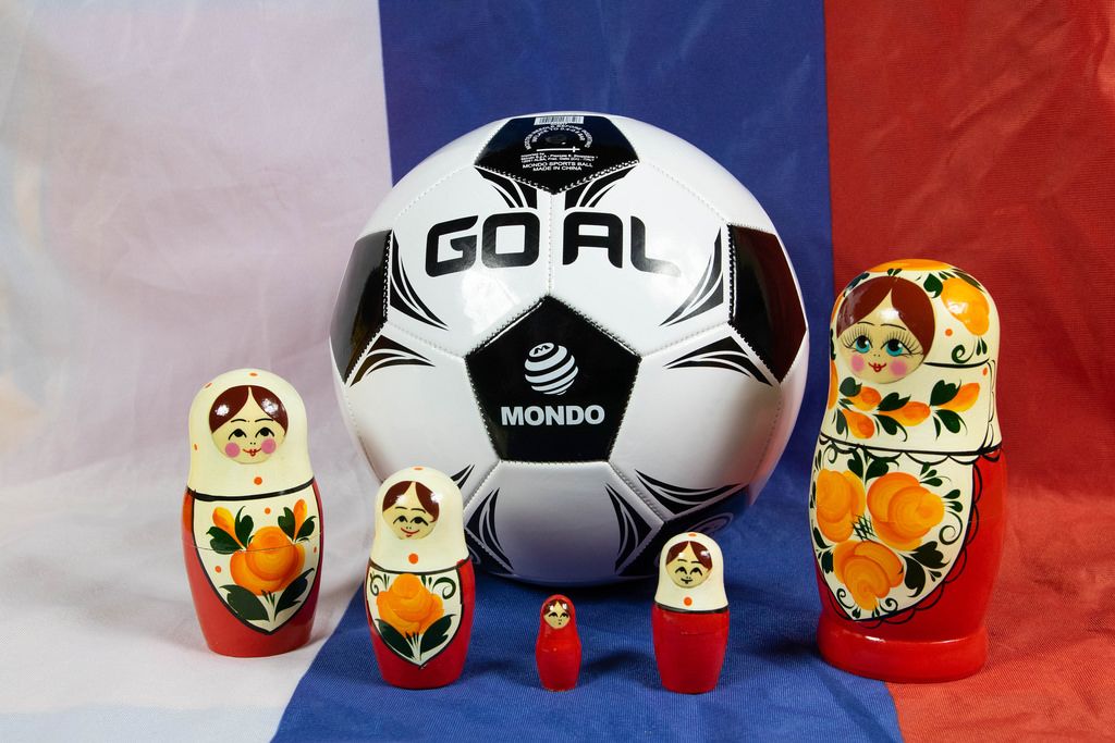 Matryoshka dolls standing around soccer ball on Russian flag