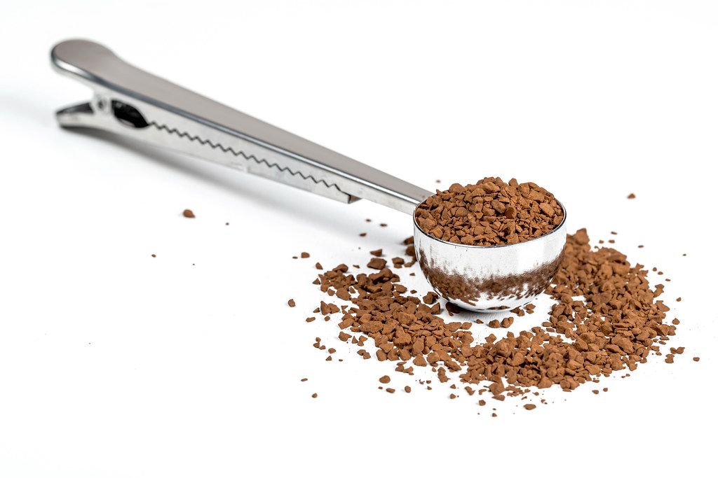 Measuring spoon with instant coffee on a white background