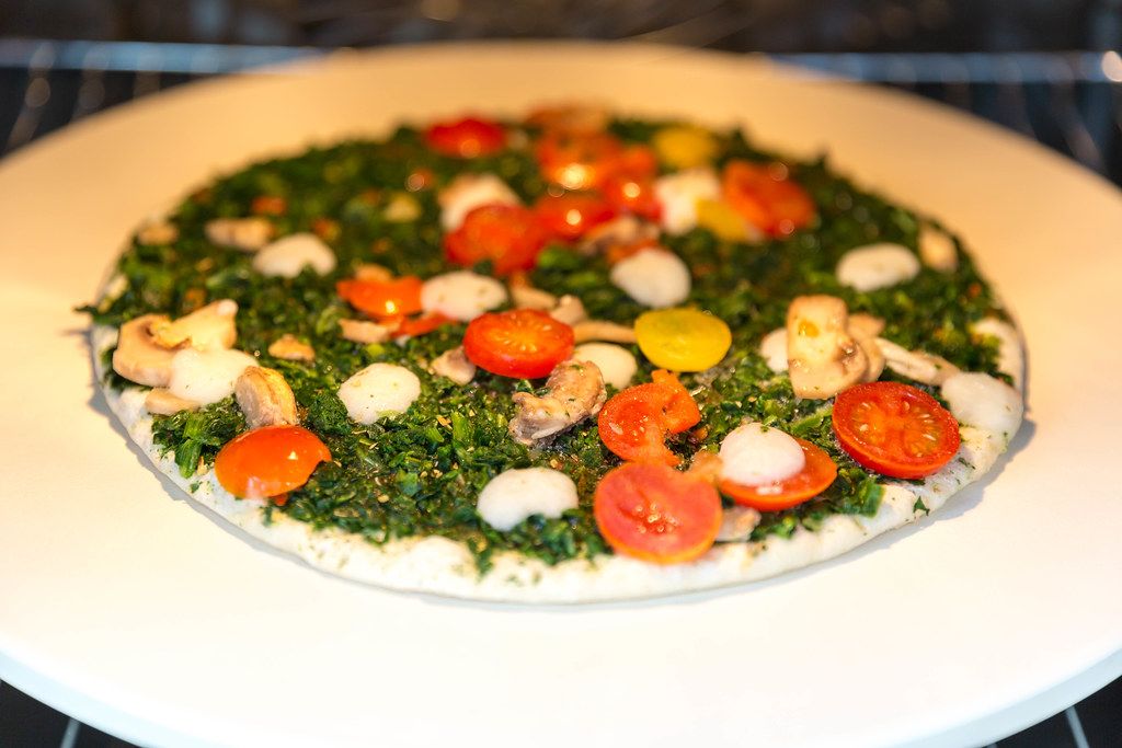 Meatless pizza Verdura by Trattoria Alfredo with spinach, yellow tomatoes and mushrooms in the oven on a pizza stone by BBQ Premium