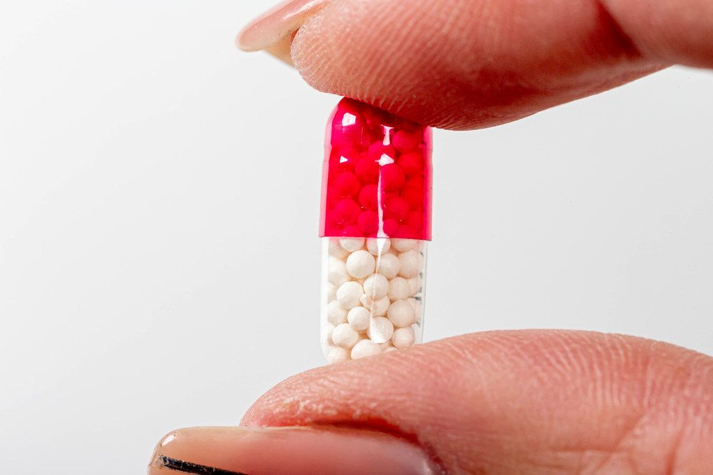 Medical care concept. Capsule with medical granules in a female hand close-up (Flip 2019)