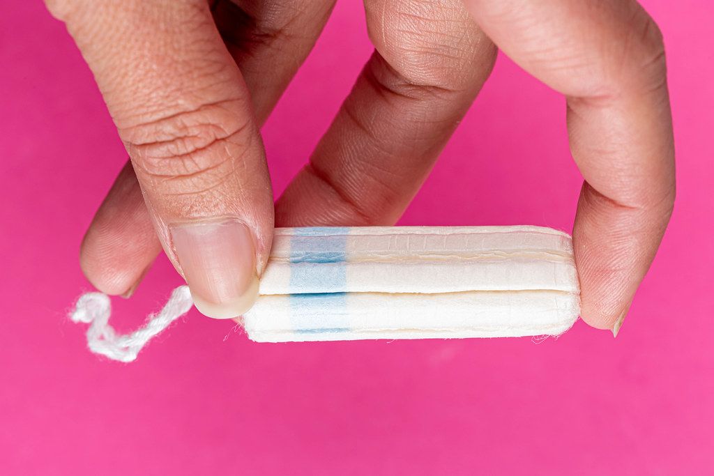 Medical female tampon on a pink background in women's hand